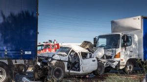 Car wedged between two trucks in Truganina